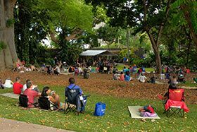 A group of people are sitting on the grass in a park.