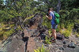 A woman with a backpack is standing on top of a rocky hill.