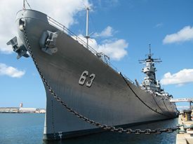 A large military ship is docked in the water.
