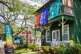 A green house with a balcony and colorful flags hanging from the trees.