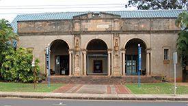 A large building with arches and a blue roof is sitting on the side of the road.