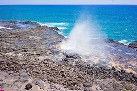 A waterfall is coming out of the ocean on a rocky shore.
