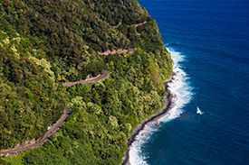 An aerial view of a winding road along a cliff overlooking the ocean.
