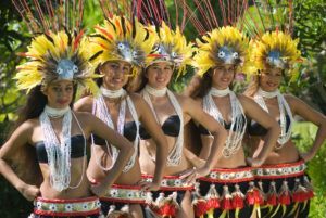 A group of women wearing feathered hats and skirts are standing next to each other.