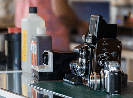 A group of cameras sitting on top of a counter next to bottles of ink.