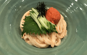 A close up of a plate of food with noodles and vegetables on a table.