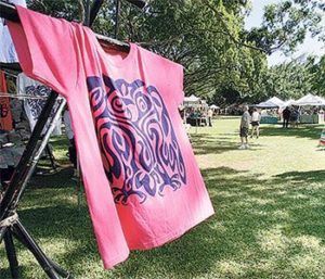 A pink t-shirt is hanging on a clothes line in a park.