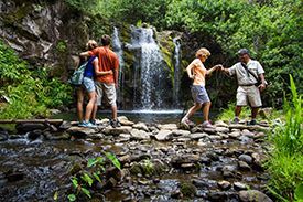 A group of people are standing next to a waterfall.