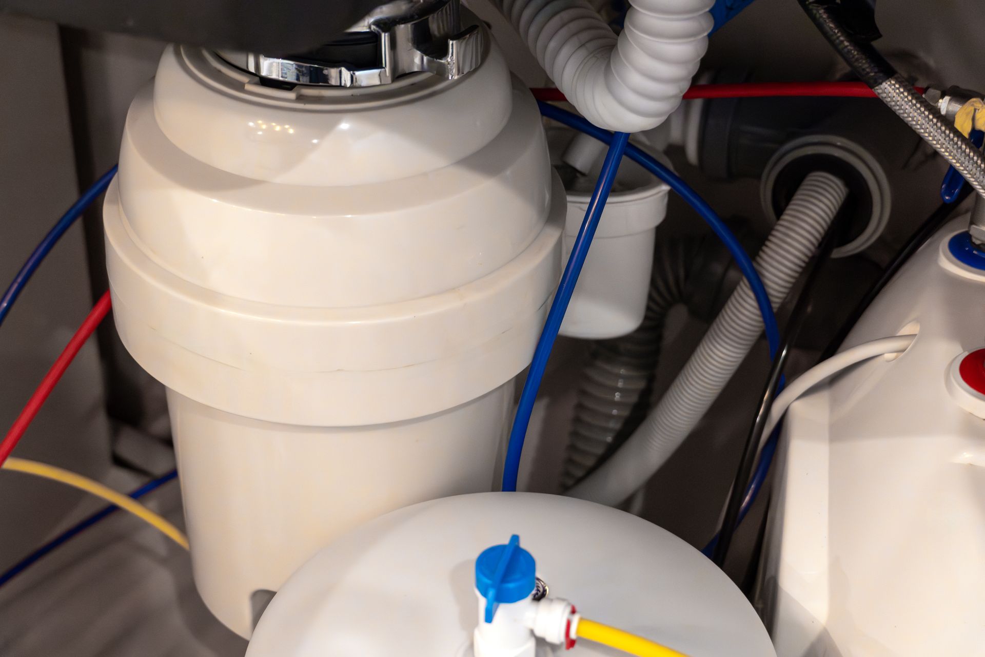 White cylindrical tank with blue and red hoses in a mechanical setup