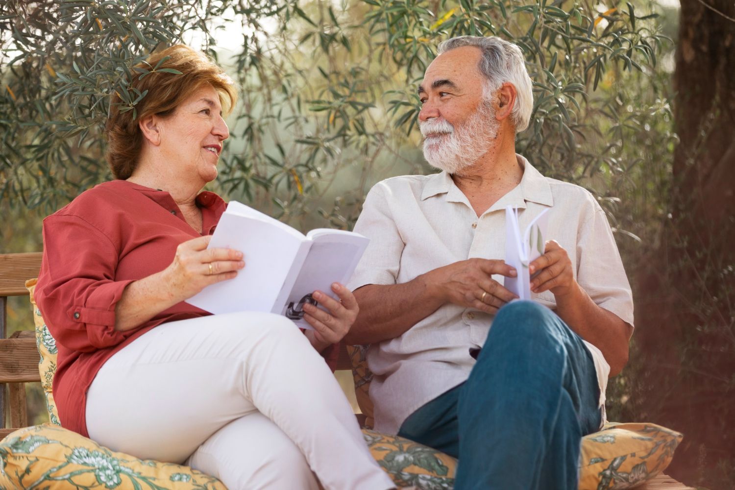 A man and a woman are sitting on a bench reading a book.