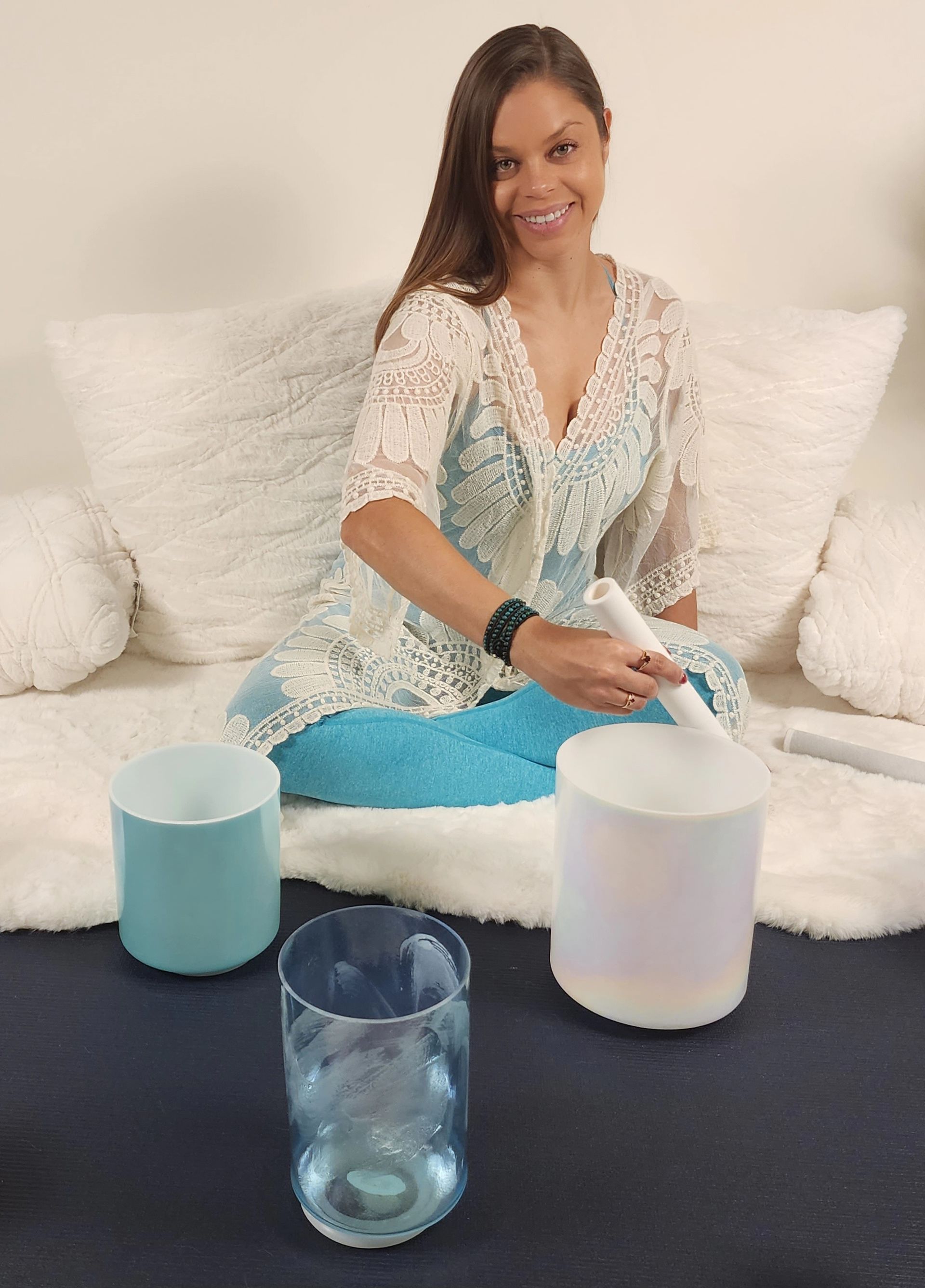 A woman is sitting on a couch playing a sound bowl.