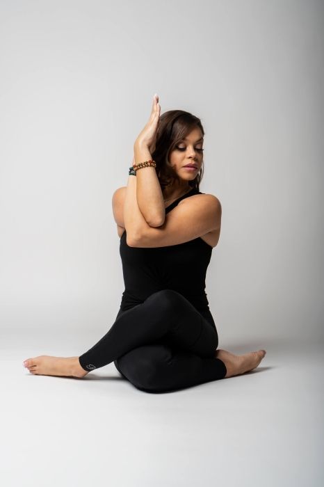A woman is sitting on the floor doing a yoga pose.