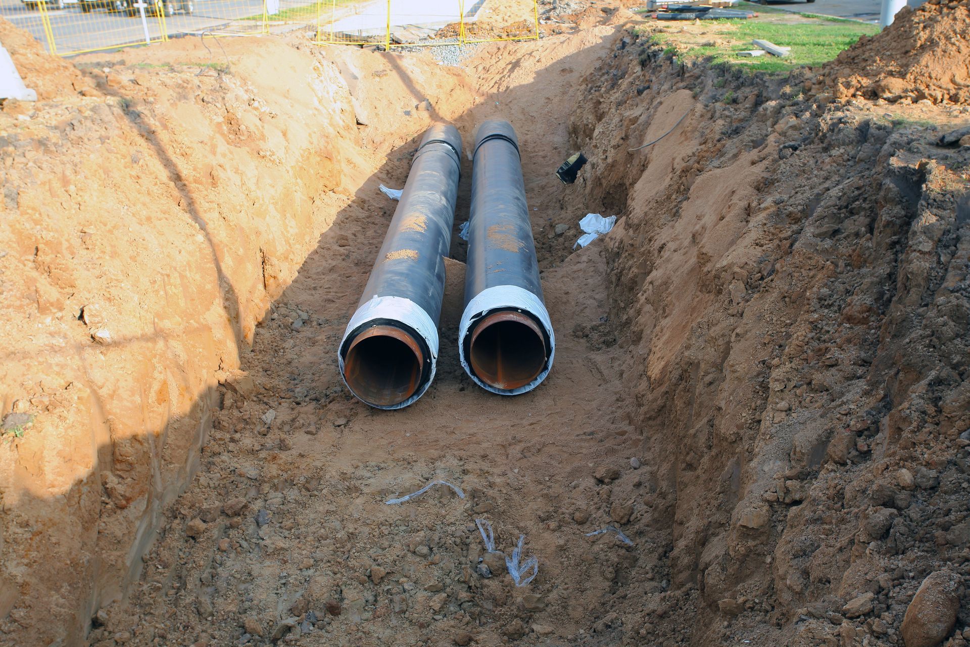 Large pipes were laid in a trench for an underground sewer line replacement project on a job site. Large pipes were laid in a trench for an underground sewer line replacement project on a job site.