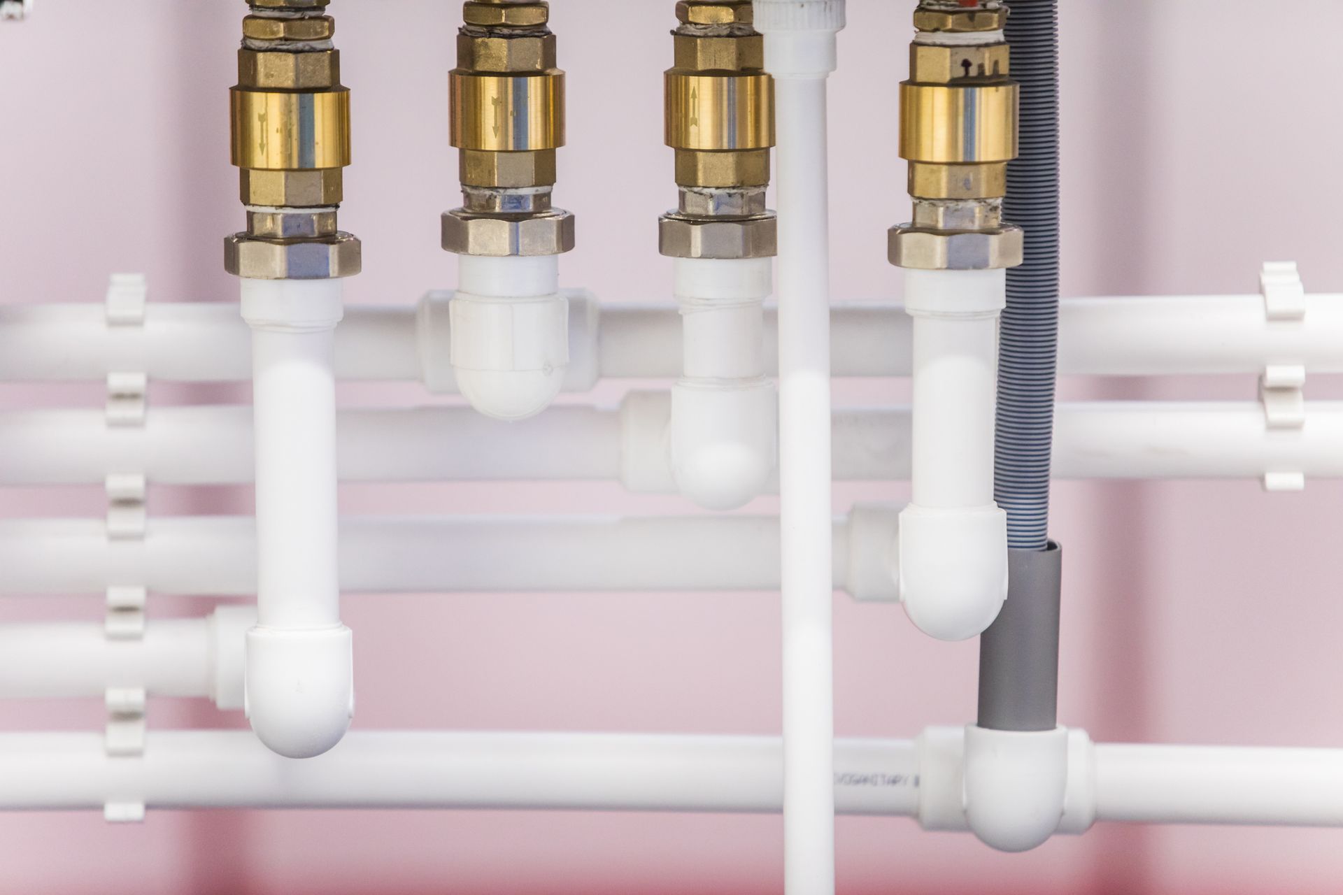Close-up of white PVC pipes and brass fittings used in a sewer line replacement project.