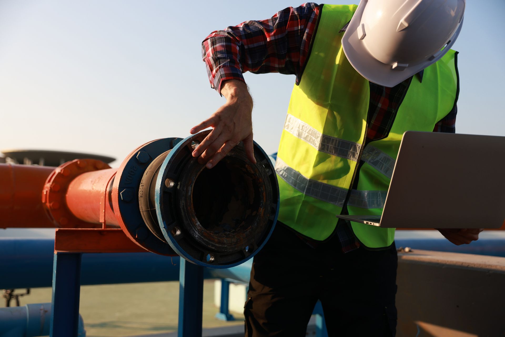 Technician inspecting large pipe during sewer line replacement project at an industrial site.
