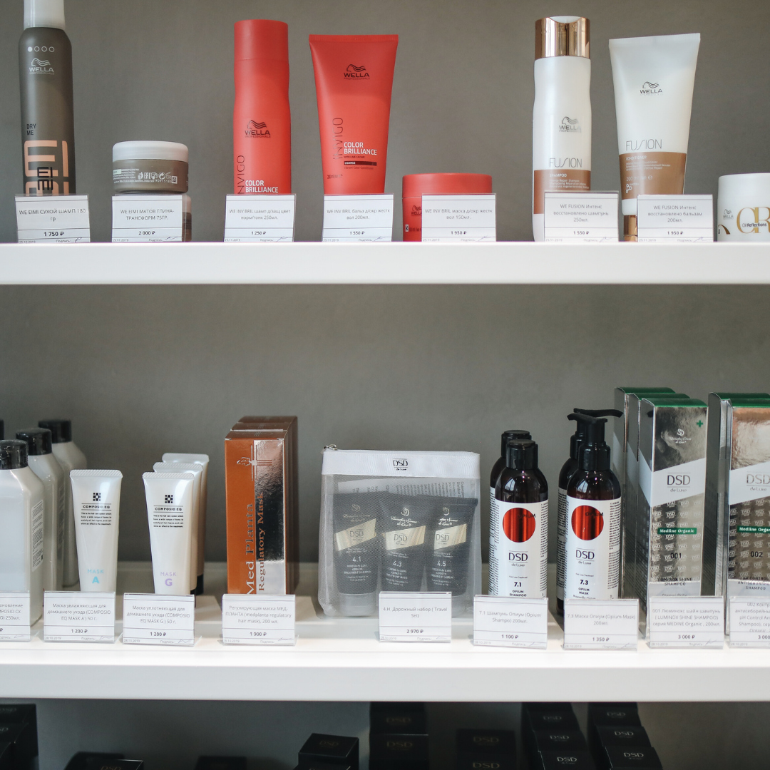 Shelves of assorted skincare tubes, jars, and boxes in white, red, and black packaging