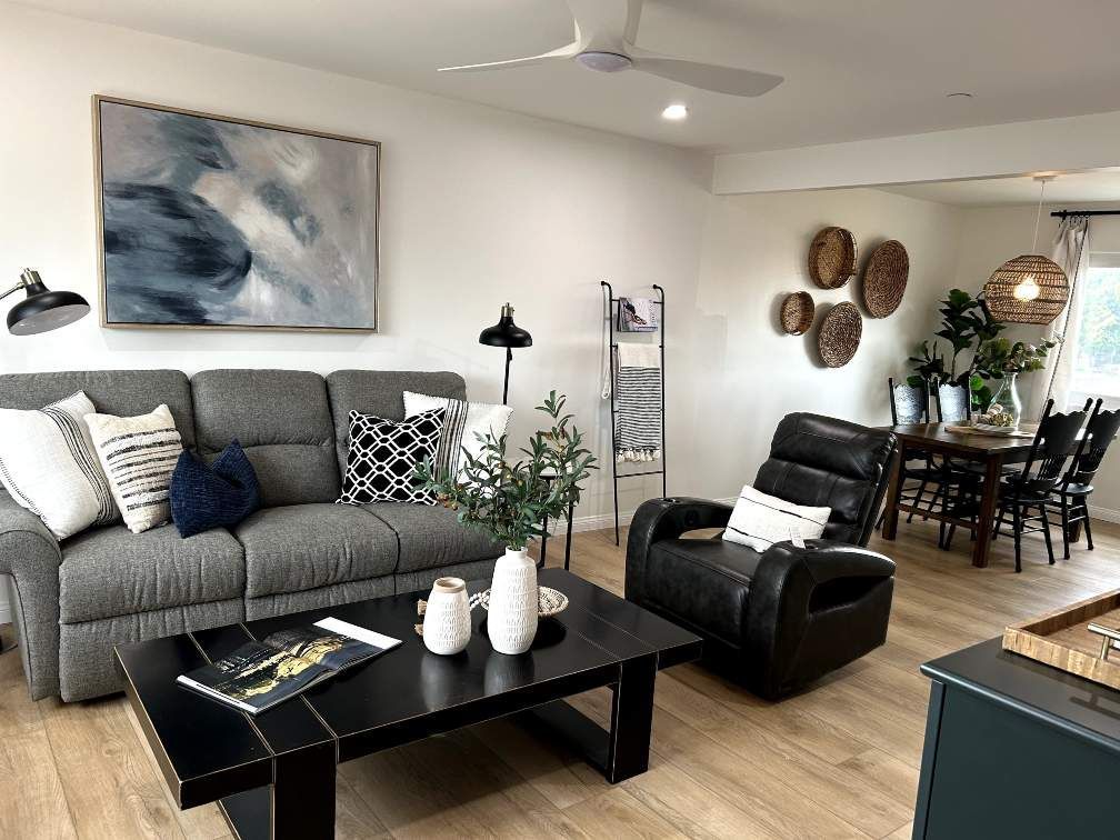 Living room with gray sofa, black recliner, abstract art, and a dining area.