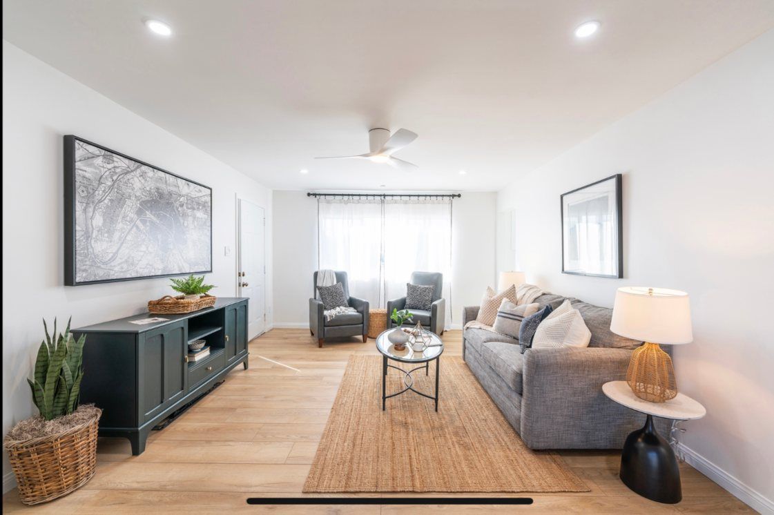 Living room with neutral tones, light wood floors, gray sofa, and black accents.