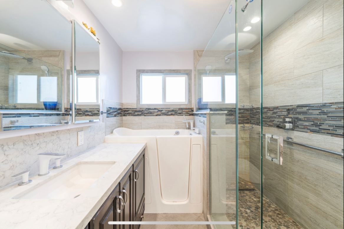 Bathroom with a walk-in tub, glass shower, vanity, and a window. Beige, white, and gray tones.