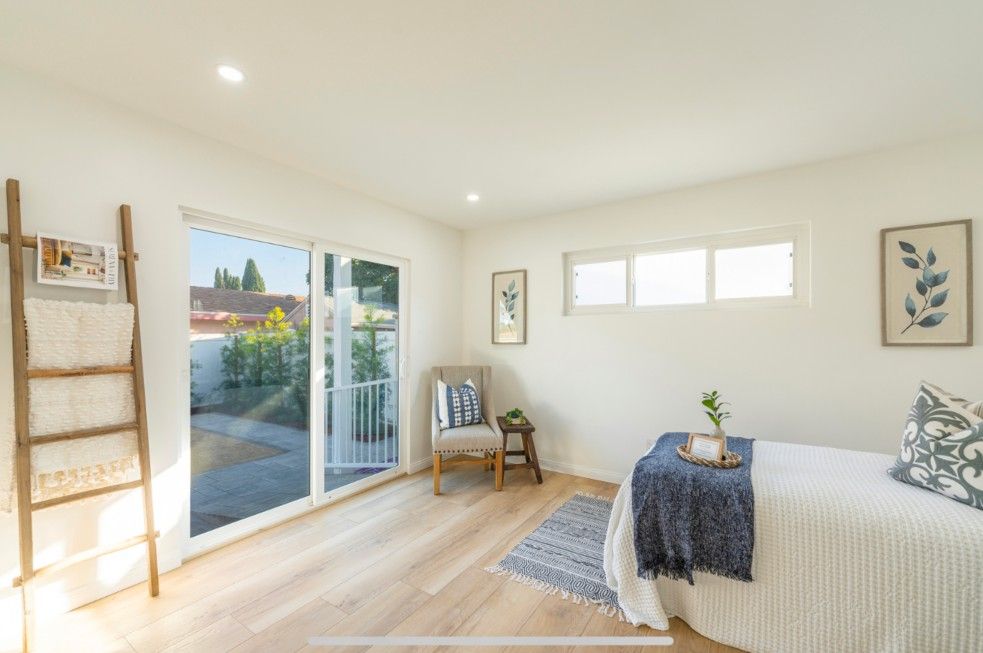 Bedroom with sliding glass door, light wood floor, white walls, and a small outdoor patio.