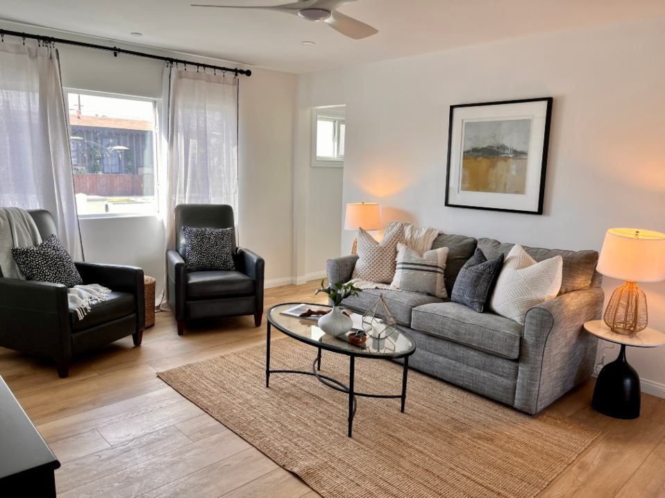 Living room with a gray sofa, two armchairs, and a coffee table on a jute rug.