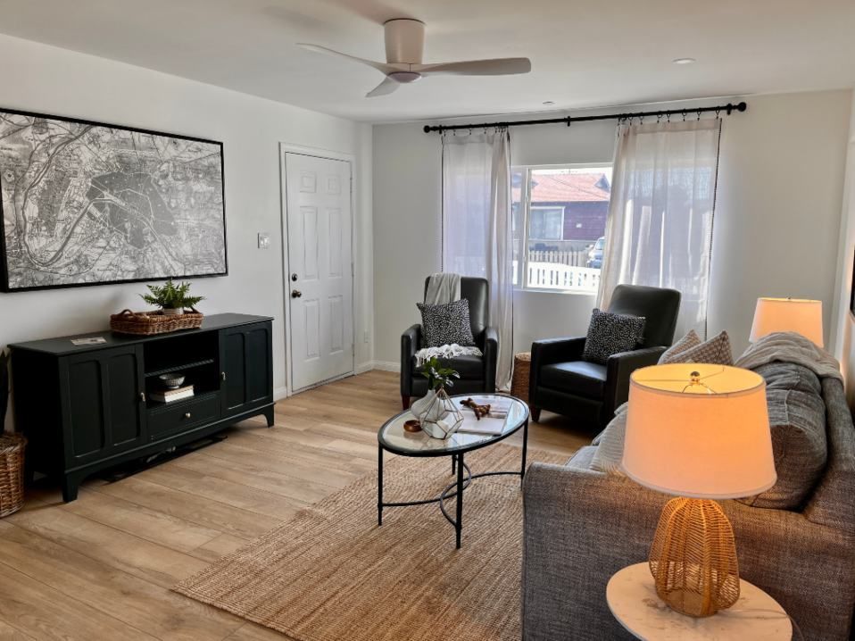 Living room with gray sofa, black accent furniture, and light wood floors.