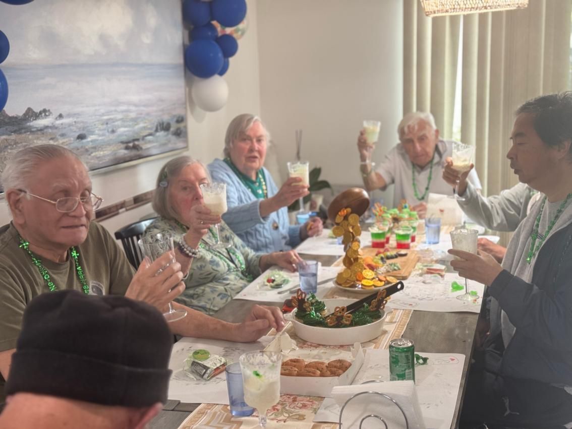 People eating together at round tables in a bright, casual dining room. Coral Tree Care Home in Lomita, CA.