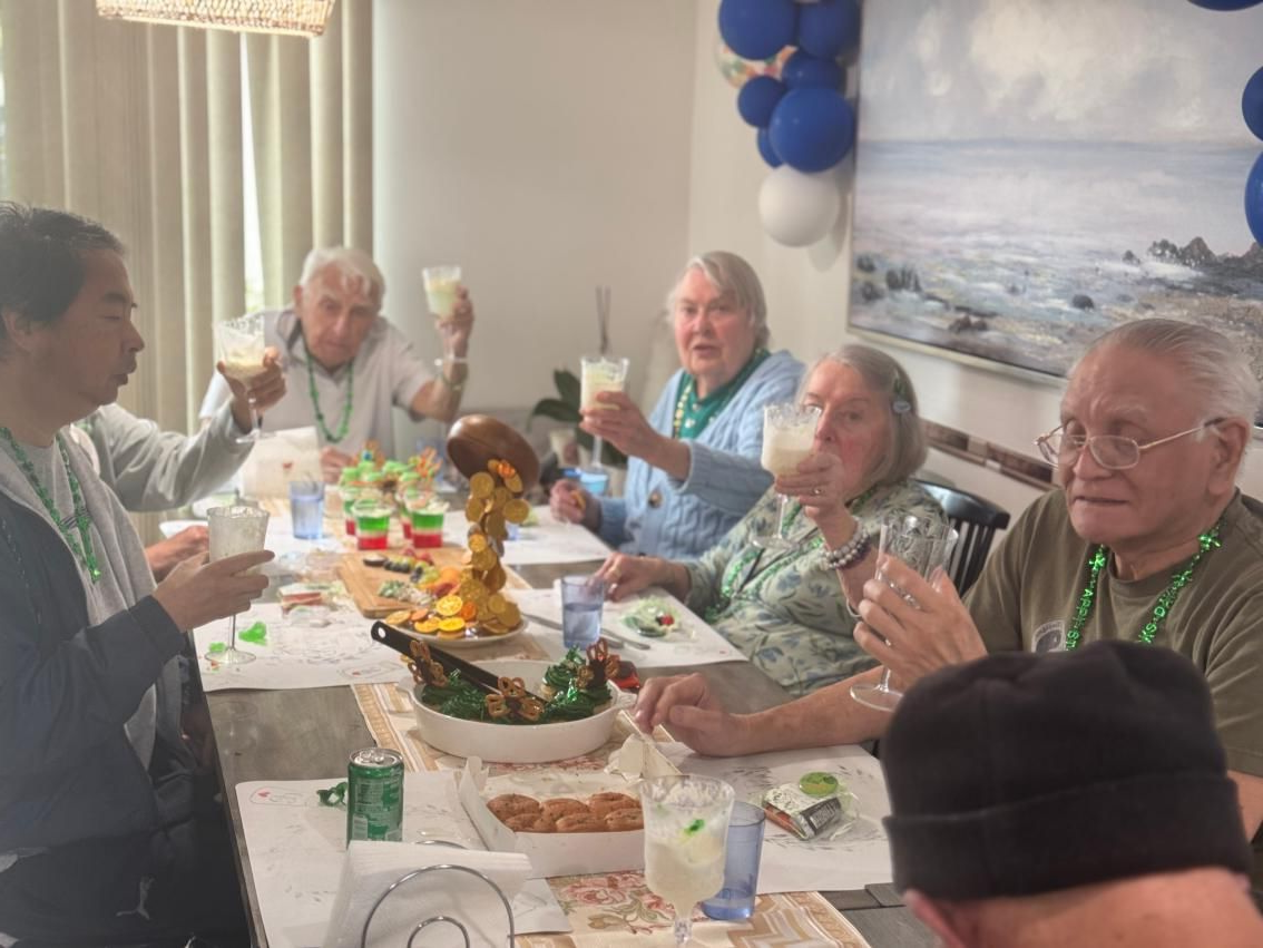 Elderly people at a table, celebrating with drinks, decorations. Coral Tree Care Home Assisted Living near Torrance, CA.