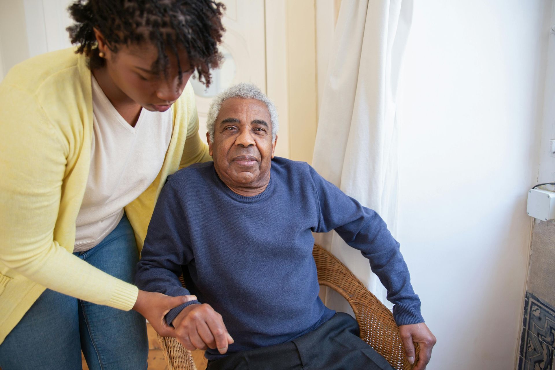 Woman assisting an elderly man from a chair. Senior care explained in Lomita, CA.