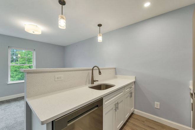 Bright modern kitchen with white countertops, sink, pendant lights, and pale blue walls