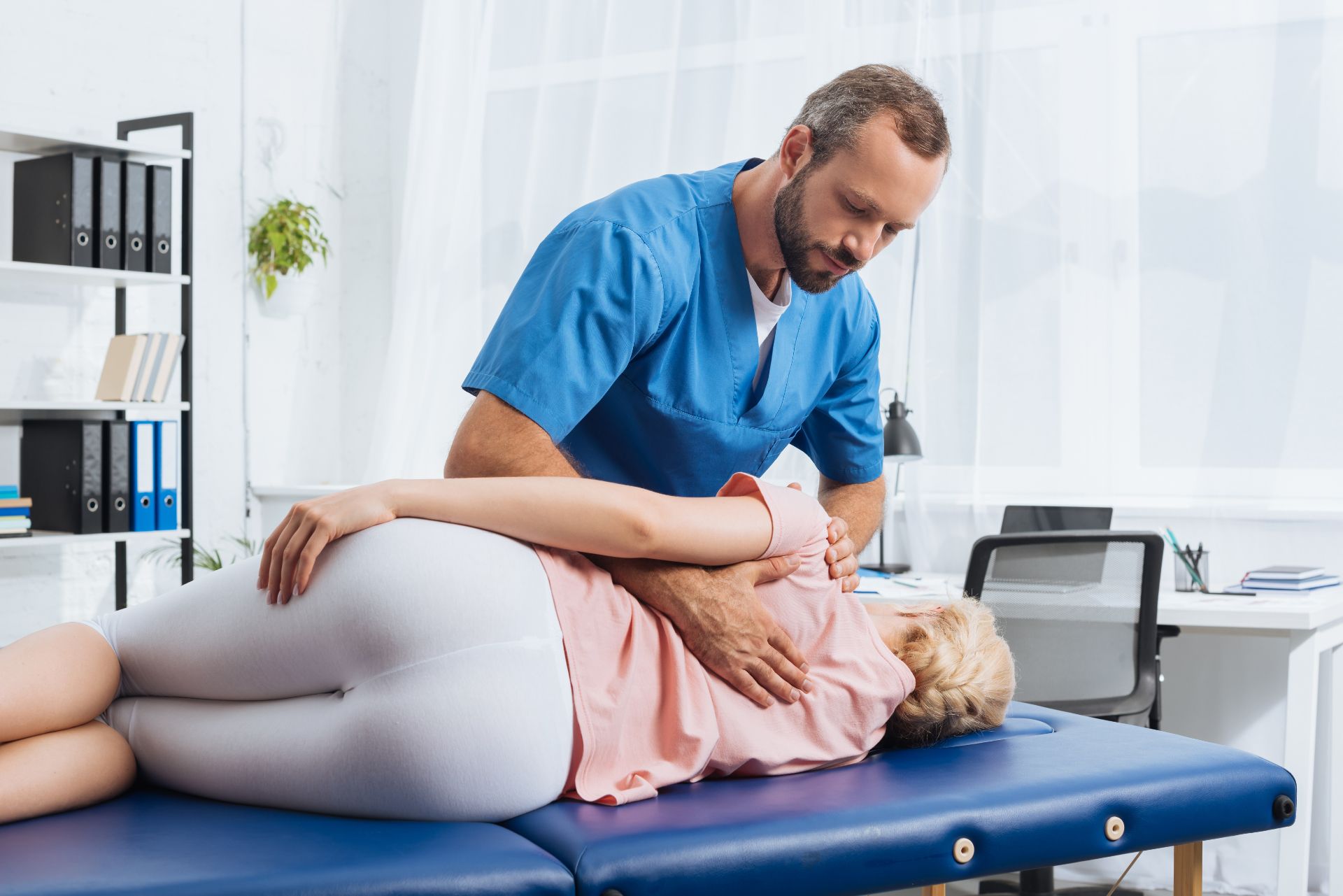 A man is giving a woman a chiropractic adjustment on a table. WellLife Chiropractic