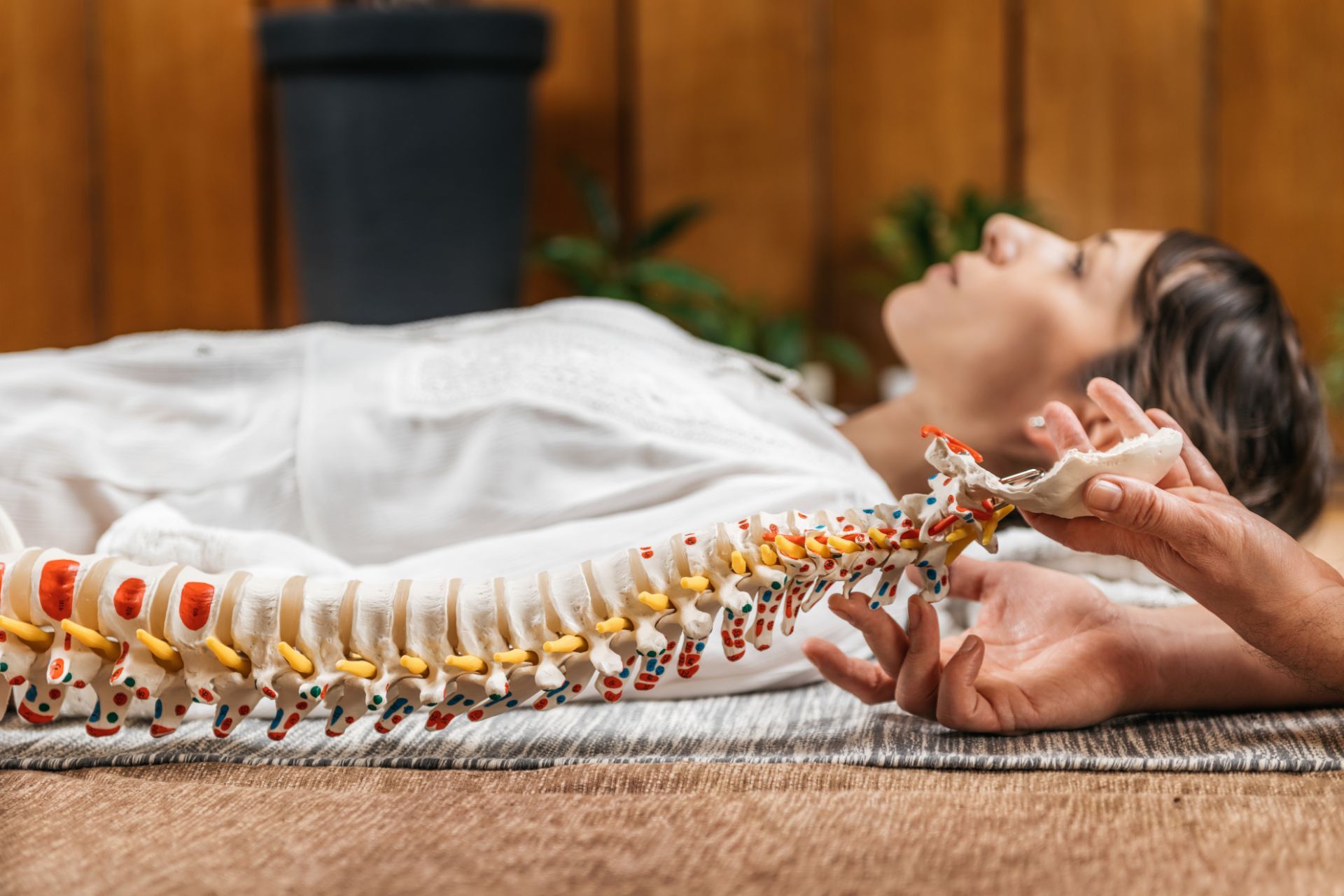 A woman is laying on the floor with a model of her spine. WellLife Chiropractic