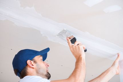 Professional worker repairing a ceiling corner during a drywall service in Moreno Valley, CA.
