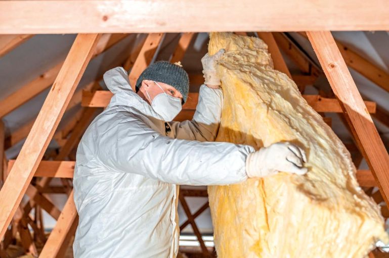 A worker installs fiberglass insulation in attic during Insulation Installation Service in Moreno Valley, CA for comfort