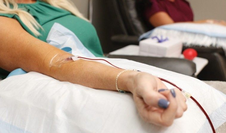 A woman is sitting in a chair with a needle in her arm.