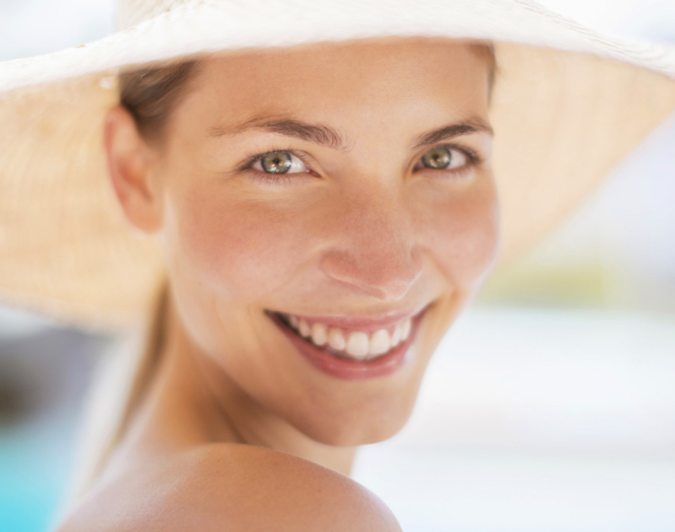 A woman wearing a hat is smiling and looking over her shoulder