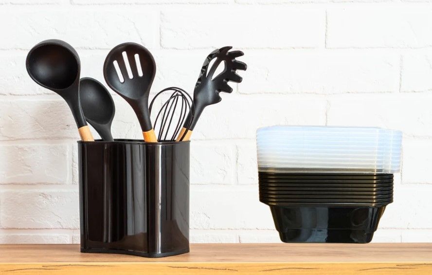 A stack of plastic plates and utensils on a wooden shelf.
