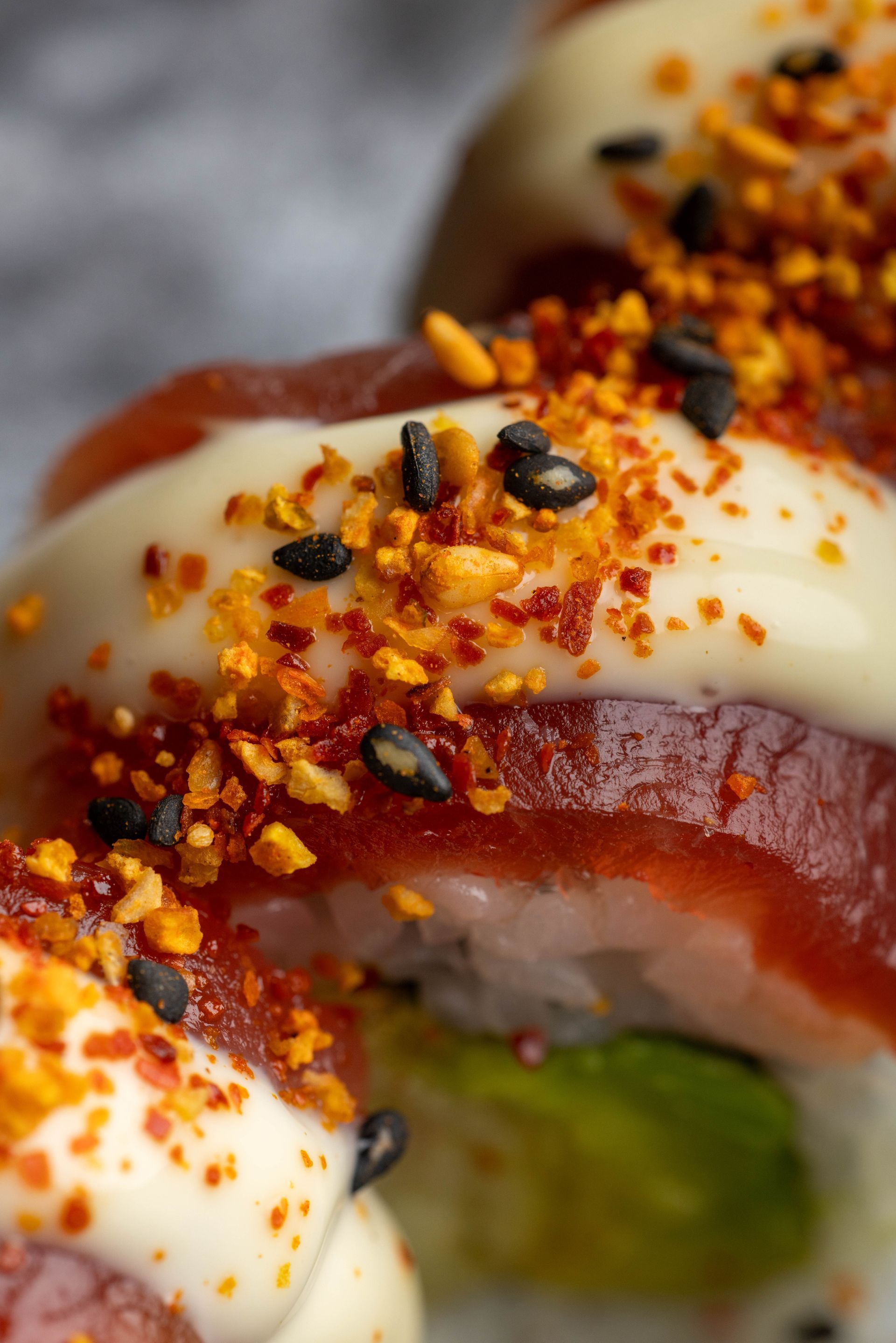 Close-up of a glazed pastry topped with white icing, red syrup, and orange sprinkles