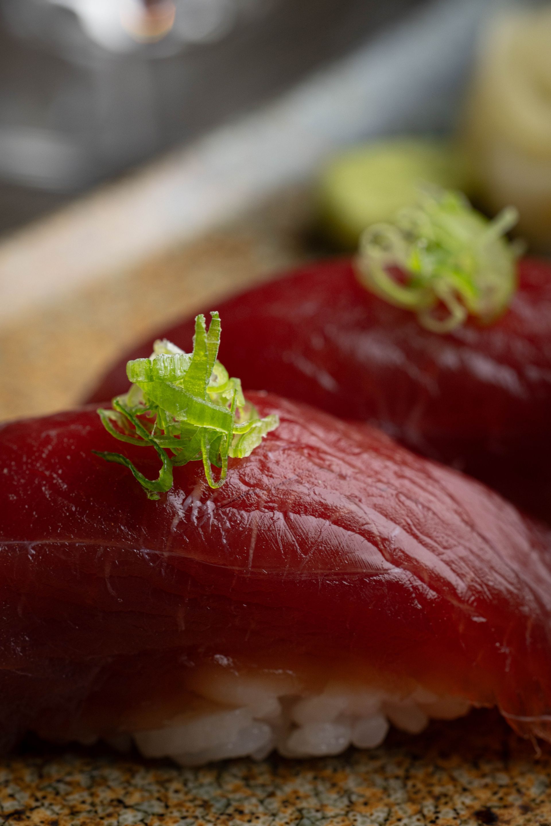 Close-up of tuna nigiri sushi with white rice and green garnish