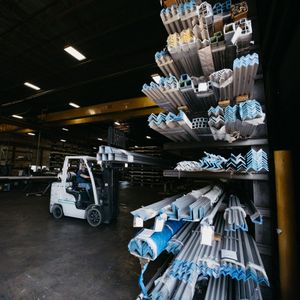 Forklift moving metal beams in a warehouse.