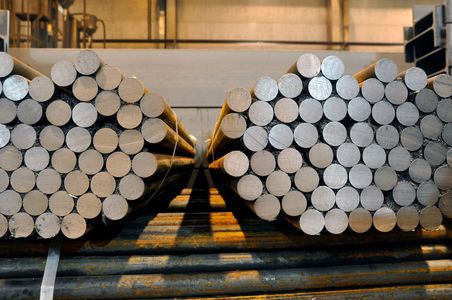 Bundles of round metal bars stacked together in an industrial setting.