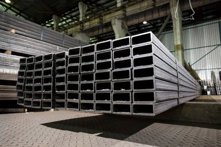 Stacks of rectangular steel tubes in a warehouse setting.