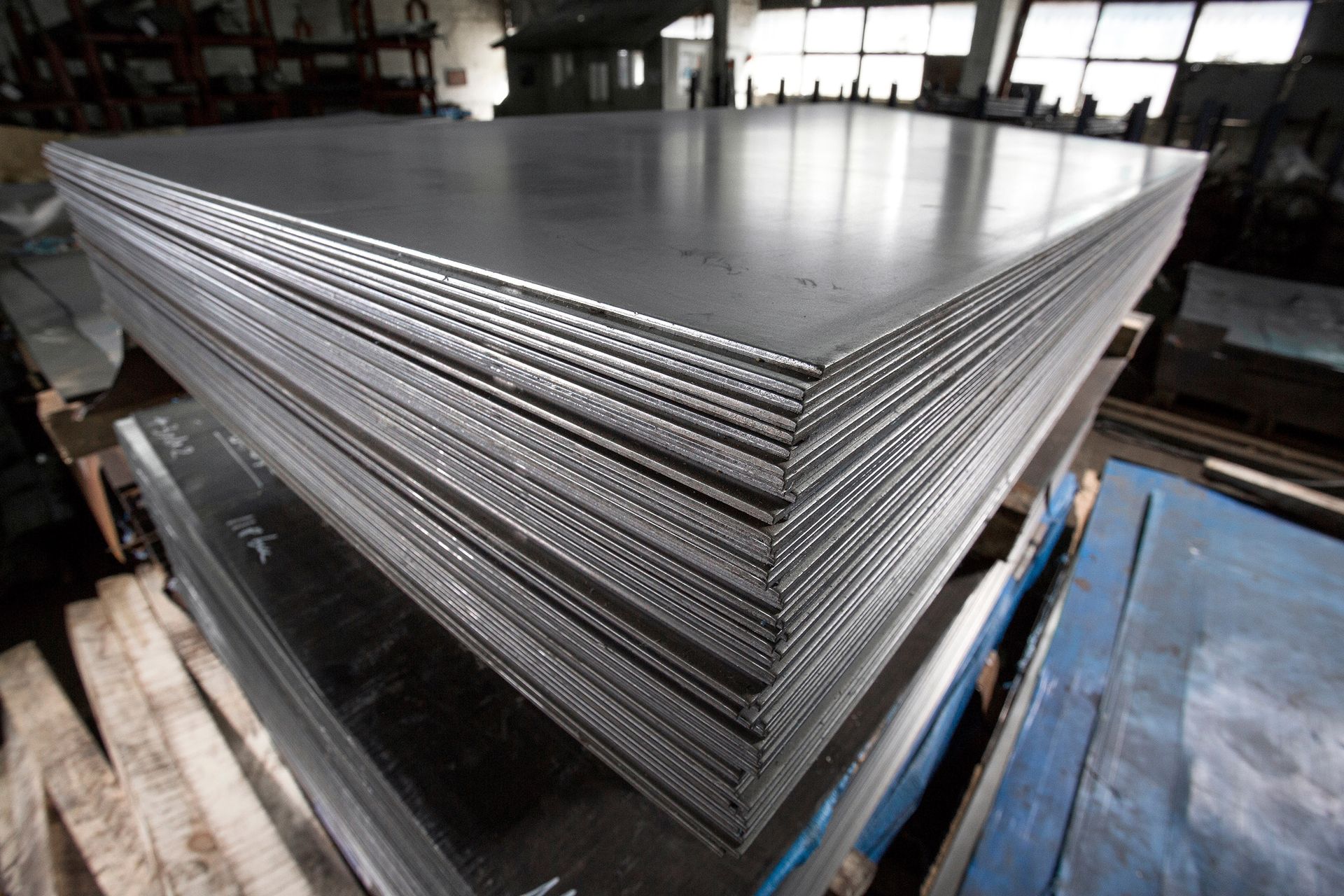 Stack of steel sheets in a workshop, ready for use.