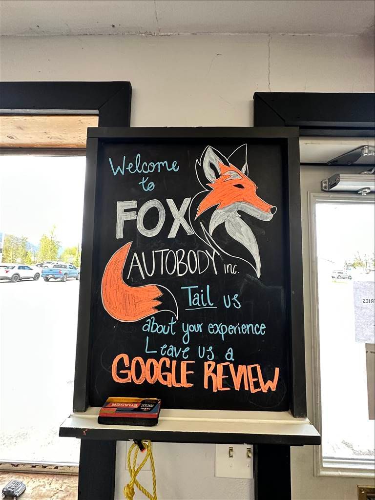Chalkboard sign for Fox Autobody with fox drawing, text invites customers to leave a Google review.