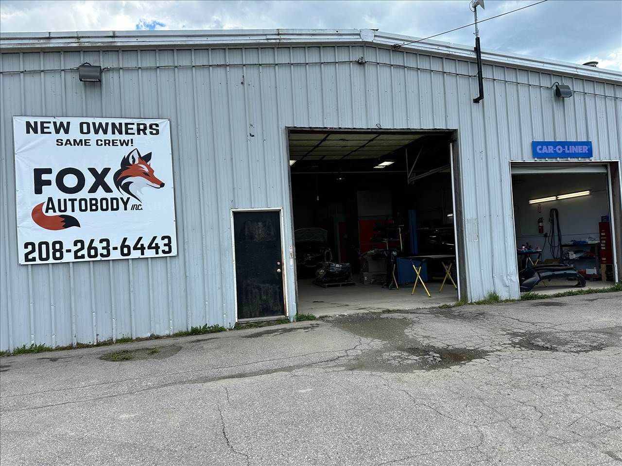 Fox Autobody shop with a sign, open garage, and phone number.