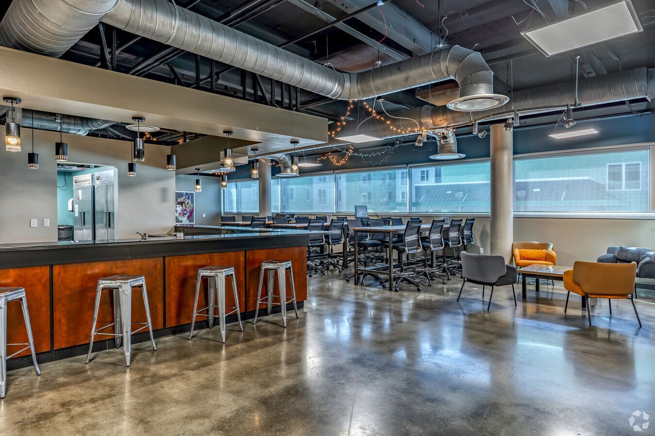 A large room with a bar and stools in it.