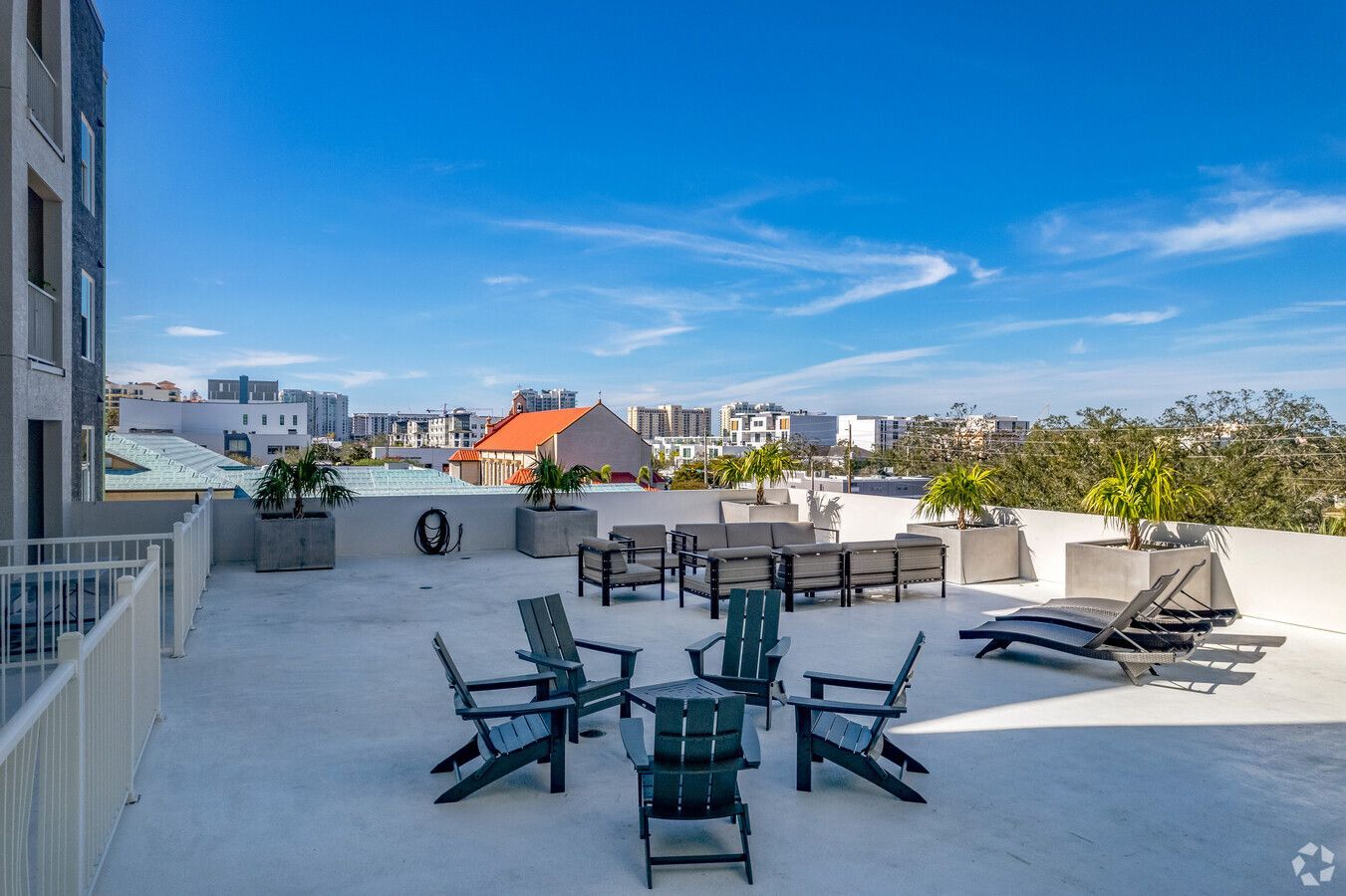 A rooftop deck with a table and chairs and a view of the city.