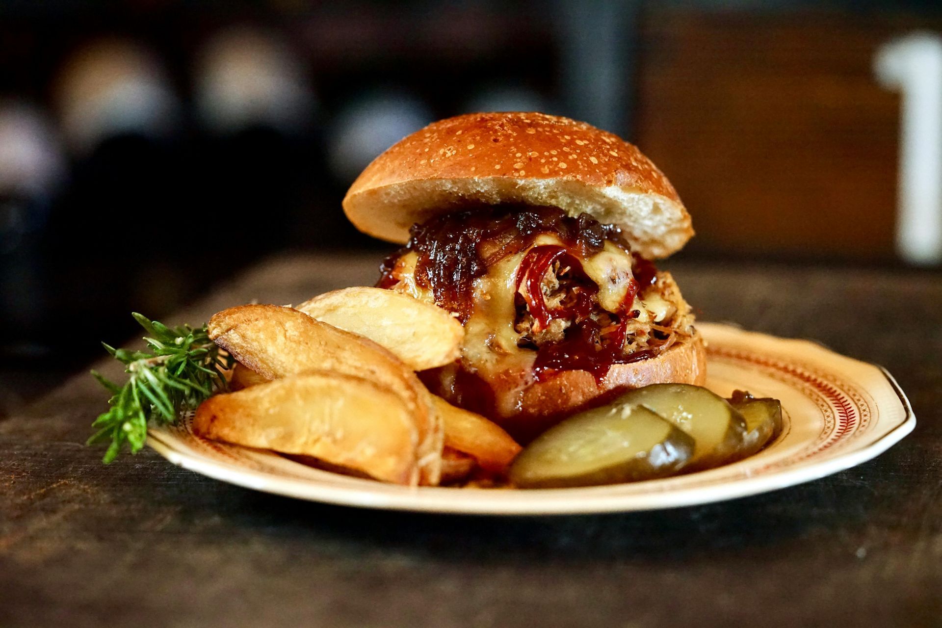 A hamburger with french fries and pickles on a plate on a table.