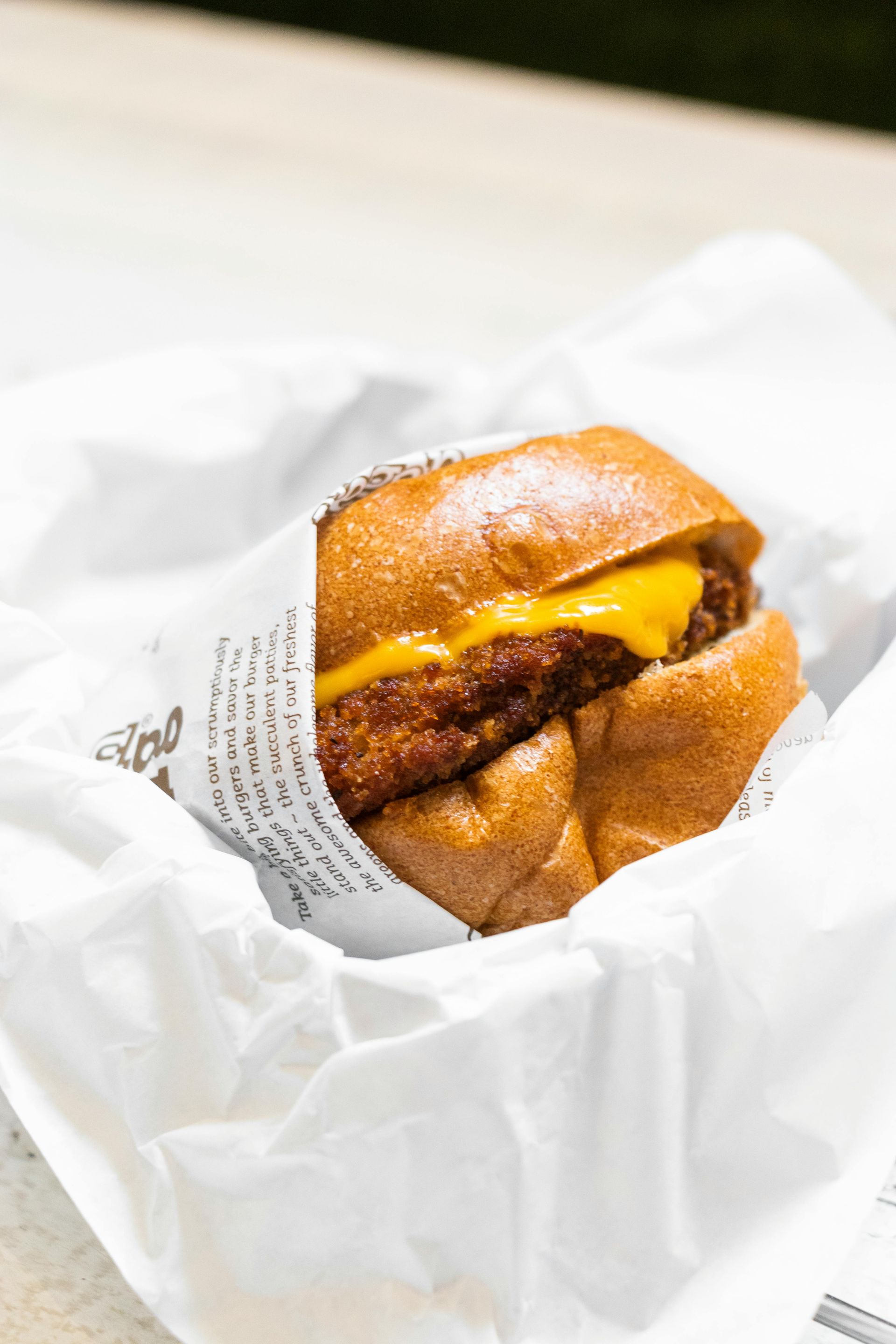 A close up of a beef sandwich wrapped in paper on a table.
