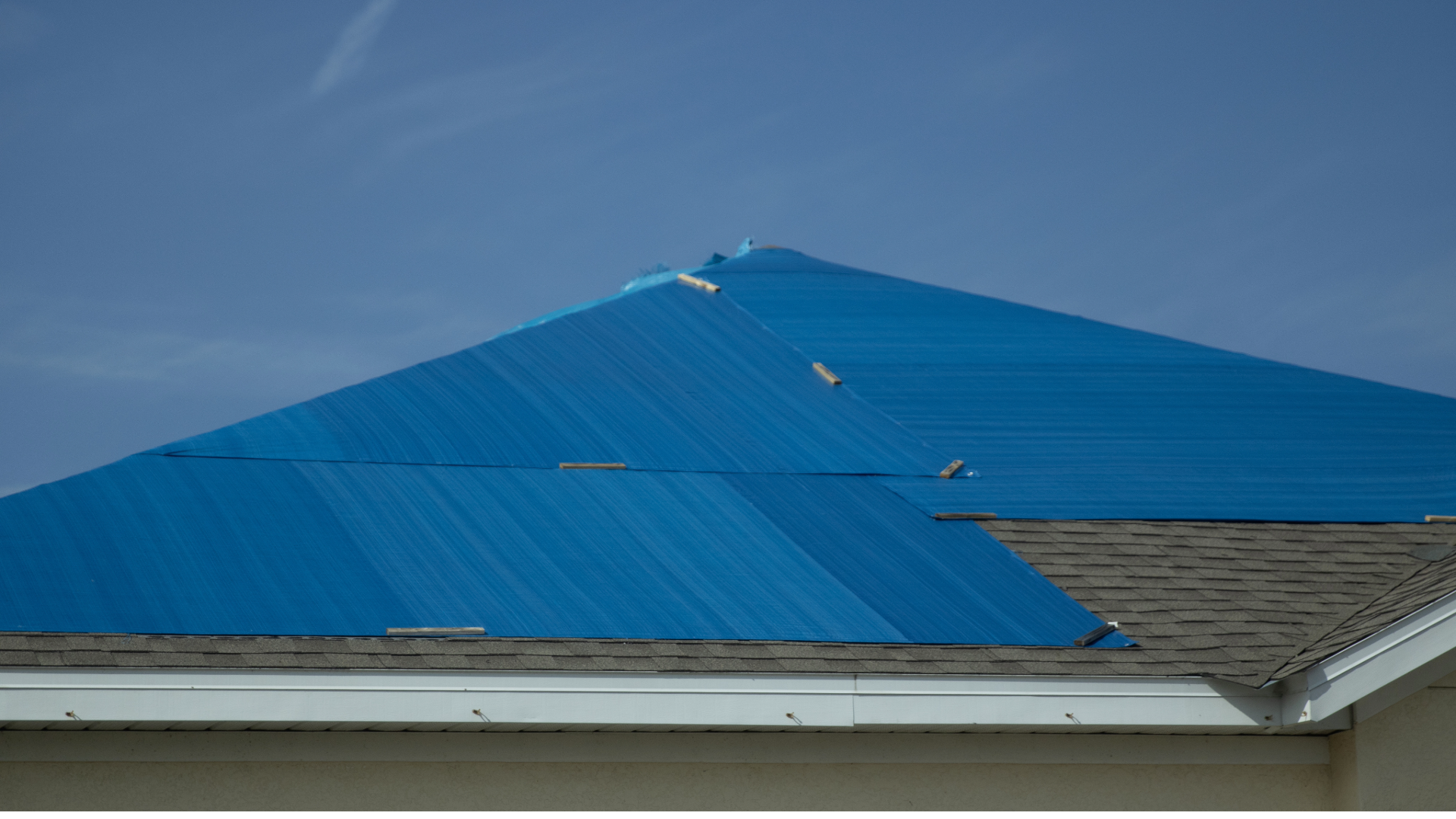 Roofing crew securing emergency tarps on storm-damaged Florida home